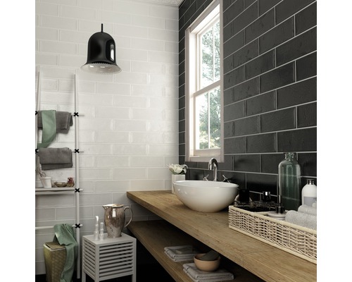 Koupelna s bílými a černými obdélníkovými obkládačkami, umyvadlem a dřevěnou policí