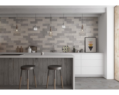 Moderní kuchyně s šedými obkladovými cihlami, barovým pultem s barovými stoličkami a bílými skříňkami.