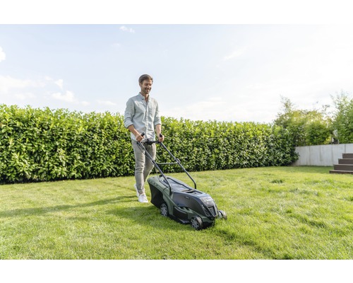 Žena připravuje sekačku Bosch na trávu na zahradě