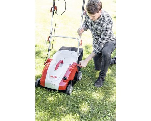Muž obsluhuje provzdušňovač trávníku značky AL-KO na zahradě.
