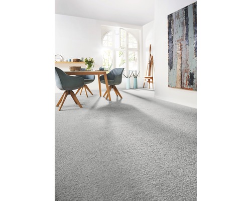 Světlý obývací pokoj s kobercem, jídelním stolem a uměleckým dílem