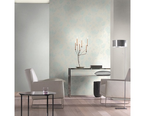 Světlý obývací pokoj s květinovou tapetou, křesly a stojací lampou.