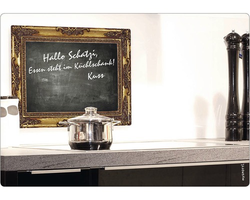 Černá tabule se zlatým rámem, hrnec na varné desce