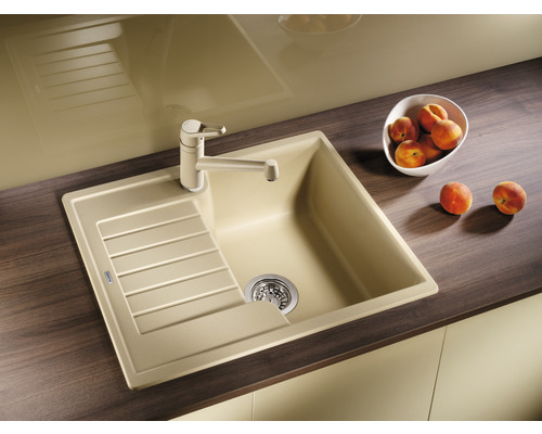 Dřez s odkapávací plochou a baterií na kuchyňské lince.