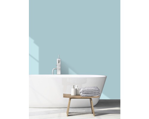 Světlá koupelna s volně stojící vanou, baterií, ručníky a dřevěnou lavicí