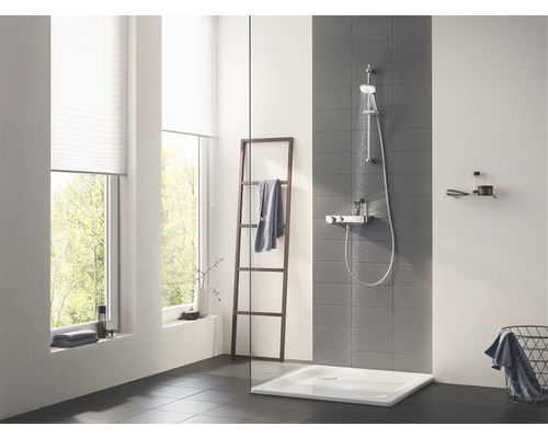 Světlá koupelna se sprchou, žebříkem na ručníky a oknem