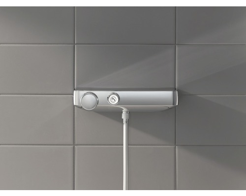 Nástěnný sprchový termostat s sprchovou hadicí před obloženou stěnou