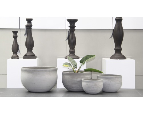 Dekorativní šedé květináče a tmavé svícny na stole