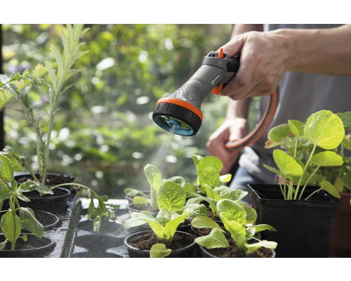 Zavlažování zahrady zahradní stříkací pistolí pro sazenice v květináčích.