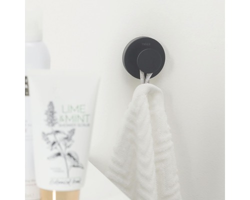 Černý háček na ručníky Tiger s ručníkem na stěně koupelny