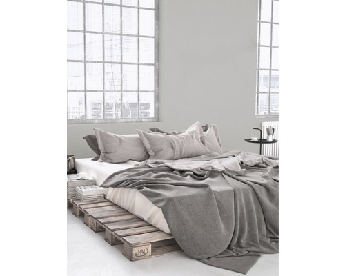 Ložnice s rámem postele z dřevěných palet, ložním prádlem a polštáři