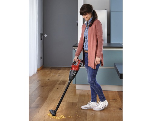 Žena používá akumulátorový ruční vysavač Einhell na dřevěné podlaze v kuchyni.