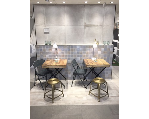 Výstavní místnost se dvěma stoly a sedadly, obloženým pozadím a osvětlením.