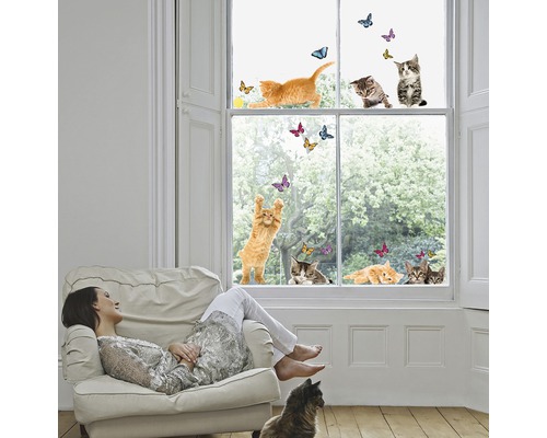 Žena odpočívá v křesle před oknem s nálepkami koček a motýlů.