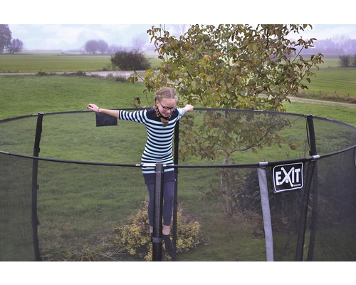 Dívka balancuje na zahradní trampolíně se sítí. Logo EXIT.