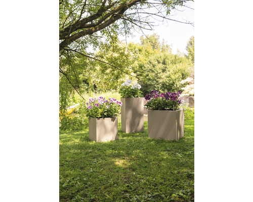 Tři osázené květináče na trávníku v zahradě.