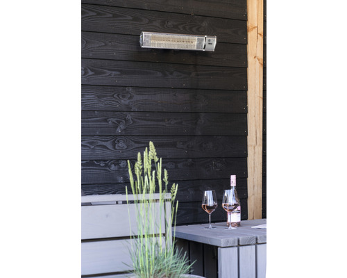 Terasa s topidlem, stolem, lahví vína a sklenicemi před tmavým dřevěným obložením