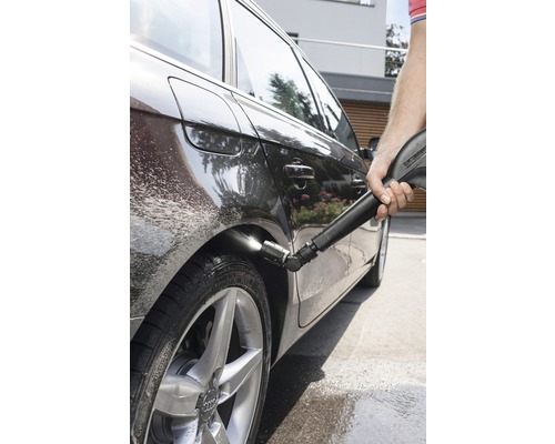 Osoba čistí auto pomocí vysokotlakého čističe.