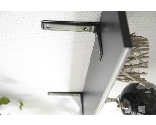 Černá nástěnná police s držáky na bílé zdi