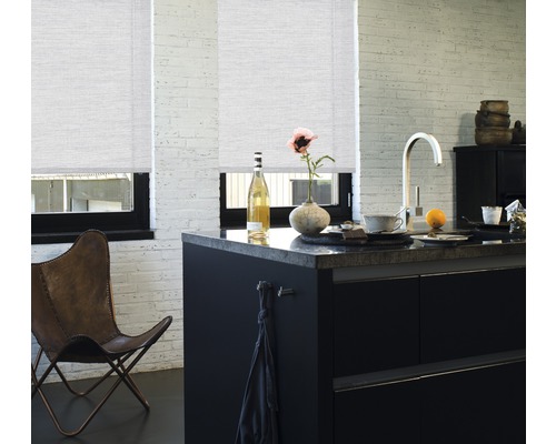 Světlá kuchyně se dvěma roletami v oknech, černým kuchyňským ostrůvkem a koženou židlí
