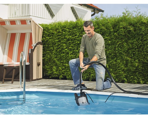 Muž obsluhuje ponorné čerpadlo k vyprazdňování bazénu na zahradě.