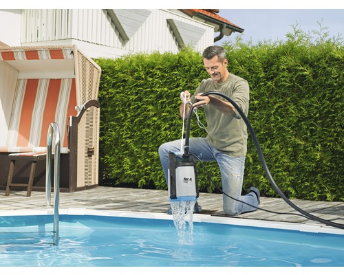 Muž používá ponorné čerpadlo u bazénu k vypouštění vody.