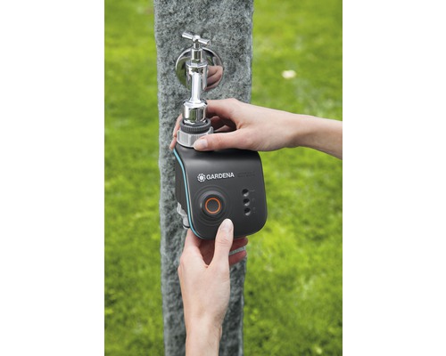 Osoba připevňuje zavlažovací počítač Gardena Smart Water Control na venkovní vodovodní kohoutek.