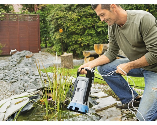 Muž obsluhuje jezírkové čerpadlo u zahradního jezírka.