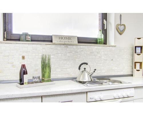 Světlá kuchyně s obkládanou stěnou, nápoji a kuchyňskými potřebami na pracovní desce