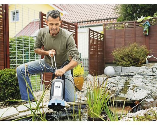Muž obsluhuje jezírkové čerpadlo značky for.q v zahradním jezírku.