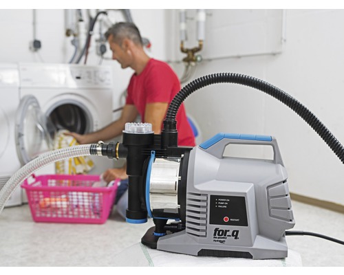 Domácí vodárna používaná v prádelně s osobou, která dává prádlo do pračky