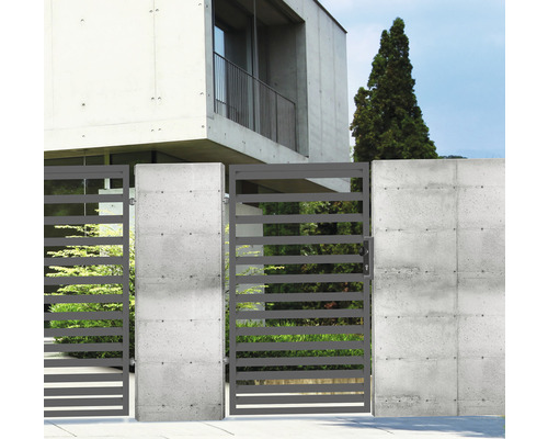 Horizontální kovové plotové brány s betonovými sloupky před moderním obytným domem.