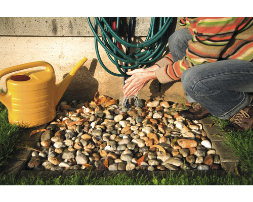 Scéna zavlažování zahrady se žlutou konví, zahradní hadicí a osobou, která si myje ruce