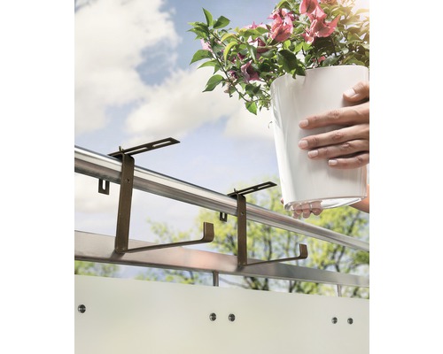 Osoba zavěšuje držák na květináč na balkonové zábradlí