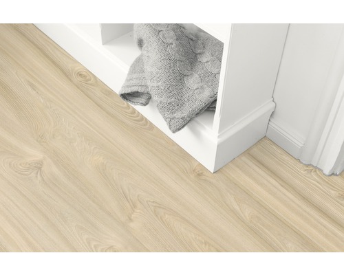 Světlá dřevěná podlaha vedle regálu s pletenou dekou