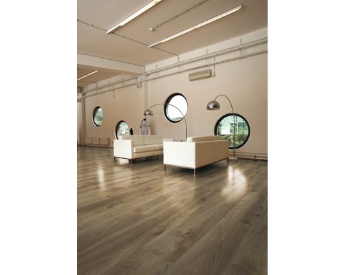 Světlý pokoj s dřevěnou podlahou, pohovkami a kulatými okny.