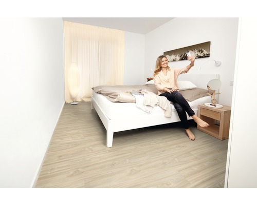 Světlá ložnice s dřevěnou podlahou, postelí, nočním stolkem a denním světlem