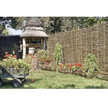 Scéna s zahradní studnou, proutěným plotem, květinovým vozíkem a osázenými proutěnými truhlíky