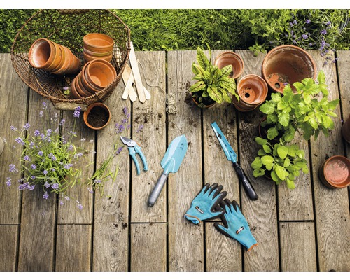Zahradní scéna s květináči, rostlinami, zahradním nářadím a zahradními rukavicemi na dřevěném stole