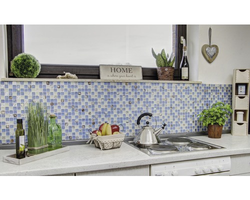 Kuchyňská scéna s mozaikovými obklady, dekoracemi a kuchyňským náčiním na pracovní desce.