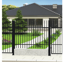 Černý kovový plot před obytným domem se zahradou.