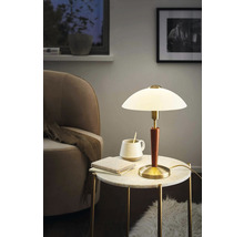 Stolní lampa na příručním stolku s knihou a šálkem v obývacím pokoji.