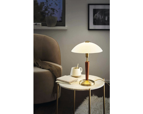 Stolní lampa na příručním stolku s knihou a šálkem v obývacím pokoji.