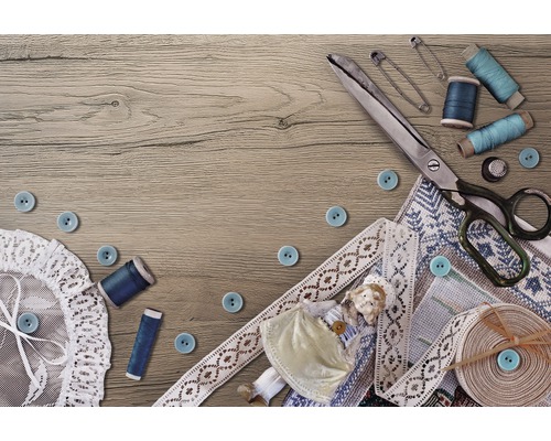 Šicí scéna s nůžkami, knoflíky, nití, zavíracími špendlíky, krajkou a panenkou na dřevěném stole