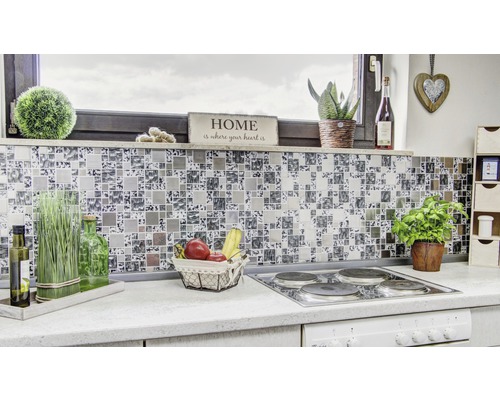 Detail moderní kuchyně s mozaikovými obklady jako zástěnou, sporákem a různými dekoracemi.