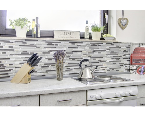 Kuchyňská scéna s mozaikovými obklady, varnou deskou, dřezem a různým kuchyňským náčiním