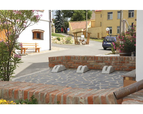 Venkovní snímek se třemi betonovými stojany na kola před cihlovou zdí