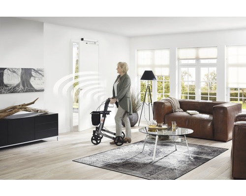 Žena s chodítkem v obývacím pokoji s automatickým pohonem dveří