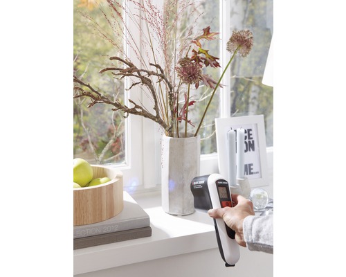 Scéna s infračerveným teploměrem používaným na okenním parapetu před oknem.