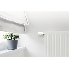Radiátor s elektronickým termostatem, záclona a pokojová rostlina na parapetu
